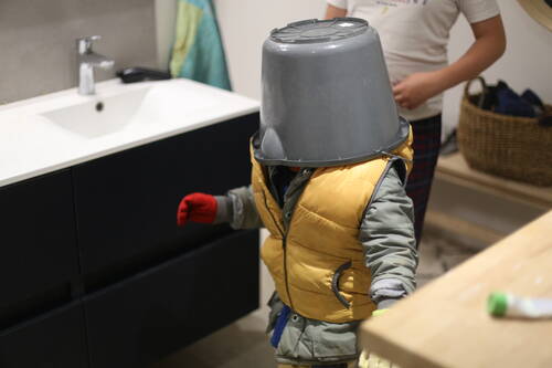 A kid playing astronaut with a bucket on their head