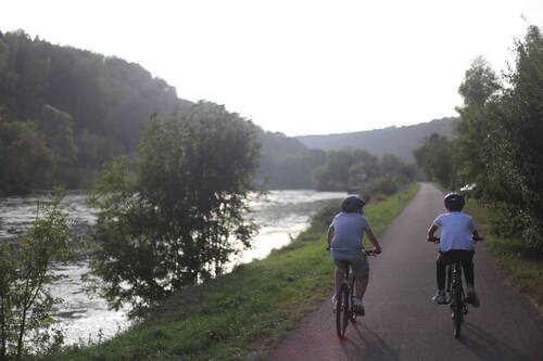 Two teenagers riding their bike along a river