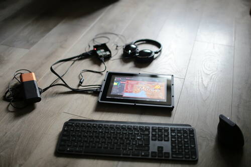 Un écran sans fil, un clavier sans fil et un souris sans fil posés par terre. L’écran affiche le jeu OpenRA sur Raspbian OS. L’écran est attaché à une batterie nomade, un raspberry pie et un casque audio.