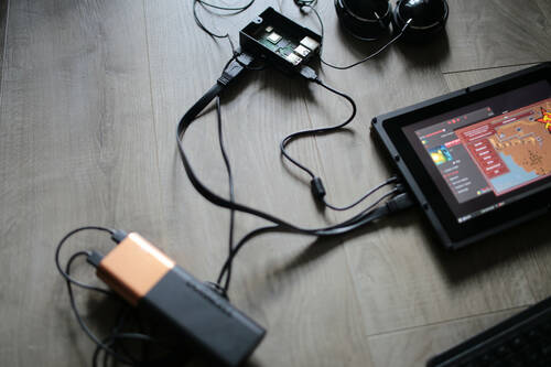 A screen on a ground displaying OpenRA on Raspbian OS. The screen is plugged to a battery, a raspberry pi and an headphone.
