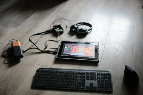 A wireless keyboard, a wireless mouse and screen on a ground. The screen display OpenRA on Raspbian OS. The screen is plugged to a battery, a raspberry pi and an headphone.