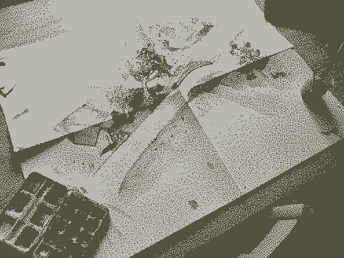 Image pixelisée : Aquarelle d’un petit village en vue isométrique. Posée sur une table avec des pinceaux et de la peinture autour.